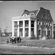 View of the residence of Margaret Long, a Denver physician, at 2070 North Colorado Boulevard in Denver, Colorado; a woman (possibly Margaret Long) sits in an automobile parked in the driveway.