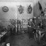 Interior view of a bicycle repair shop in Denver, Colorado; shows men, a workbench, tools, and posters of women.