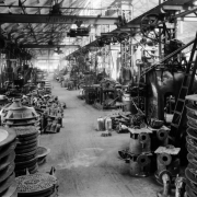 Interior view of the machine shop of General Iron Works at 1245 Osage Street in the Lincoln Park neighborhood of Denver, Colorado. Manhole covers, molds, machinery, and mobile overhead cranes are in the warehouse building.