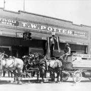 View of the Tivoli Union Brewery beer wagon and team of horses, in Denver, Colorado; storefront sign reads: "Tivoli Beer T.W. Potter Barber Billiards."