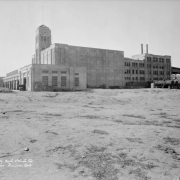 View of the Blayney-Murphy slaughterhouse at 45th (forty fifth) and Gilpin Streets in the Elyria Nieghborhood of Denver, Colorado; shows a concrete building with truck bays, a tower, and smokestacks.