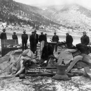 Men and boys (including Japanese) stand in the snow at the UMW camp for coal miners on strike against CF&I in Forbes, Las Animas County, Colorado; mattresses, clothes, and household items are in a pile.