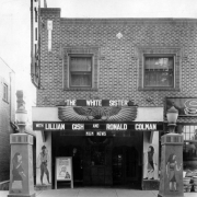 View of the Egyptian Theater at 2644 West 32nd (Thirty-second) Avenue in the Highland neighborhood of Denver, Colorado. The two-story brick building is painted with Egyptian figures and has a sign that reads: "The White Sister" and "With Lillian Gish and Ronald Colman MGM News."