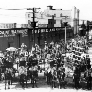 Employees of the McPhee-McGinnity Manufacturing Company pose on horse-drawn wagons near the company's warehouse at 23rd (Twenty-third) and Blake Streets in the Five Points neighborhood of Denver, Colorado. Lettering on the one-story corrugated metal building reads: "Paint Warehouse McPhee and McGinnity Company."
