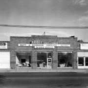 View of Abbey Rents at 350 Broadway in the Baker neighborhood of Denver, Colorado. Signs on the one-story brick building read: "Abbey Rents & Sells Party & Sickroom Supplies Oxygen 24 Hour Service" and "Everything for the Party Folding Chairs Table China Glassware Silverware Hollowware."