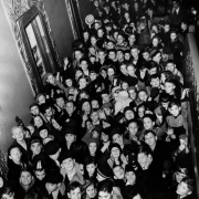 Boys and girls crowd into a hallway of the Paramount Theater designed by Temple Hoyne Buell at 16th (Sixteenth) and Glenarm Streets in Denver, Colorado. The children wait to be seated for a free movie.