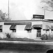 View of a business on Brighton Boulevard in Denver, Colorado; signs read: "Brannan Sand & Gravel Co. Lightning Service," "Brighton Blvd." Awnings (by Daniel Manufacturing Company) cover windows.