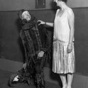Portrait of Denver Community Players in Denver, Colorado; William Myatt is in a jester costume, a woman in a satin flapper outfit looks on.