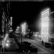 View of Curtis Street in Denver, Colorado, at night; shows theater row (Great White Way), street lights, and electric or neon signs: "Watrous Cafe," "Isis Theater," "The Nan King," "Iris Theatre, 5 Cents Pictures," "Pool," "Billards," "Princess," and "Alto."