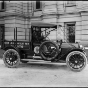View of a delivery truck in Denver, Colorado; shows a man driving, tire chains, and lettering: "Kohler-McLister Paints - the Mark of Quality" and "1621 Arapahoe St."