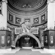 View of the Victory Theater in Denver, Colorado; shows the arched entry, ornate plaster work, and the ticket window. Display depicts a cowboy with pistols and reads: "Richard Dix, in Womanhandled."