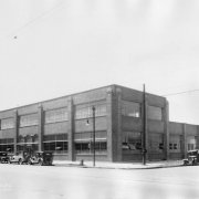View of the Meade and Mount Construction Company building at 27th (Twenty-seventh) and Larimer Streets in the Five Points neighborhood of Denver, Colorado. Automobiles are parked near the two-story brick warehouse.