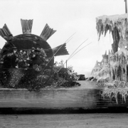 View of a parade float, built for the festival of Mountain and Plain, in Denver, Colorado. The float depicts a waterwheel and a large group of icicles.