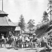 View of group of girls on donkeys with man, carriage and ornate gazebo at Ute Iron Spring Chateau, Manitou Springs, El Paso County, Colorado.