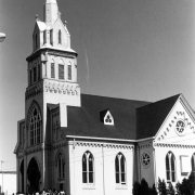 Hispanic-American men, women, and children leave after Easter Mass at the Sacred Heart Catholic Church at 2760 Larimer Street in the Five Points (Curtis Park) neighborhood of Denver, Colorado. The church building has a bell tower, stained glass windows, decorative lintels, and an arched entryway.
