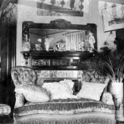 Interior view of the Henry Viley Johnson residence in Denver, Colorado; decor includes a velvet couch with pillows, a mantle with mirror, and vase of peacock feathers.