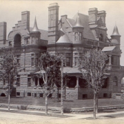 View of John A. McMurtrie home at 1007 Pennsylvania Street, Capitol Hill neighborhood, Denver, Colorado; features rusticated stone, turrets, arches, a covered porch, and ornate chimneys.