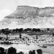 View of migrant laborers' houses near Palisade (Mesa County), Colorado. Modest frame houses are by trees and the Colorado River. Mount Garfield is in the distance.