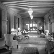 Interior view of Richthofen Castle at 7020 East 12th (Twelfth) Avenue in the Montclair neighborhood of Denver, Colorado. Chairs, a sofa, grand piano, and a palm tree are in the room.