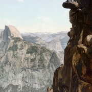 View of Glacier Point and Half (South) Dome and Yosemite Valley with group of men atop rock precipice, Yosemite National Park, California.