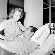 A nurse takes the temperature and pulse of Tenth Mountain Division soldier, S/Sergeant George V. Geiss as he lies in his hospital bed in Italy.