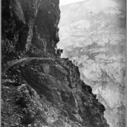 View of narrow mountain path with horse or mule rounding bend, somewhere in the San Juan Mountains, possibly near Silverton, Colorado; rocky path along narrow precipice, Rocky Mountains; photograph attributed to McClure, original by William H. Jackson.