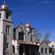 View of St. Patrick Mission Church (1907-1910: Henry James Manning, Francis C. Wagner, architects; restoration 1979: Congleton Architect ) at 3325 Pecos Street in the Highland neighborhood of Denver, Colorado. The mission style church has curvilinear parapets with copper domed towers, an arched entrance and red tile roofs.