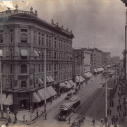 View of 16th (Sixteenth) and Larimer Streets in Denver, Colorado. Shows the Tabor Block and the Daniels and Fisher Dry Goods Store at 16th and Lawrence Streets. Signs read: "Rose & Co. Photographers," "Hotel Brunswick," and "United States Depository." A Denver Tramway Company trolley, carriages and pedestrians are in the street.