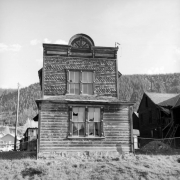 View of the two-story dilapidating wood frame residence of Jacob and Maija Kochevar, (Yugoslavian immigrants) Elk Avenue, Crested Butte, Gunnison County, Colorado; shows window frames with decorative spools and handcut imbrication made with homemade tools by Jacob's son "Jakie;" wood shingles in alternating rows of saw tooth or "dog teeth," pointed and scalloped shapes; inverted scallop along the cornice with "1913" date inside.