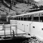Two workmen toil to reconstruct the swimming pool in Eldorado Springs, Colorado. Much of the resort was destroyed by fire in 1929. The new front facade features mission style architecture, and, "The New Eldorado Hotel," is visible in the background.