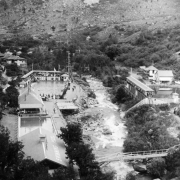 The bird's-eye view of the resort in Eldorado Springs, Colorado, shows the two swimming pools, South Boulder Creek, Crazy Staircases, and the cottages that were available for rent. People are gathered around the pool to watch swimmers and divers.