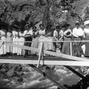 Young men and women pose on a wooden bridge over South Boulder Creek, at the resort in Eldorado Springs, Colorado. "Crazy stairways" ascend the rocky cliff in the background.