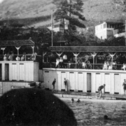 Swimmers and onlookers are at the pool in Eldorado Springs, Colorado. Changing rooms are on the far side of the pool.