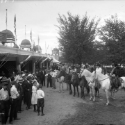 Men, women, boys, and girls look at people on horses at Lakeside Amusement Park, Lakeside (Jefferson County), Colorado.