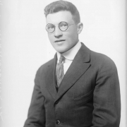 Studio portrait of E. M. Winterbourne. He wears glasses, a suit, and tie.
