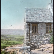 View at Charlford, near Sedalia, Douglas County, Colorado; a manor designed in 1926 for Charles Johnson by Burnham and Merrill Hoyt and built of native volcanic rock. A howitzer is by the slate roof structure.