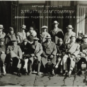 Panoramic view of the cast of Arthur Hockwold's "Struttin' Sam from Alabam'" musical company, presented at the Broadway Theater, 1756 Broadway, in Denver, Colorado. African American men and women and one white man sit and stand in front of the theater near the canopied front entrance. Sign on the canopy reads: "50 People [with] Orchestra." Sign on the window reads: "Broadway Rotisserie."