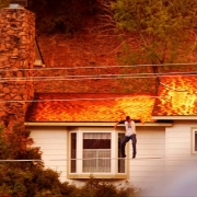 A man jumps from his roof after watering it down during the Valley Fire.