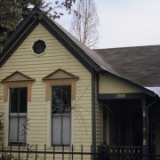 View of 2816 Curtis Street (ca. 1880) in the Five Points (Curtis Park) neighborhood of Denver, Colorado. The wooden one-story vernacular cottage has a cross-gabled roof and a small porch at the side. The residence is listed on the National Register of Historic Places as a contributing resource to the Curtis Park-Champa Street Historic District.