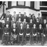A black and white photograph of members of the Tri-State Buddhist Temple. They are standing outside the church on the sidewalk.