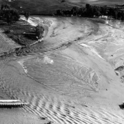 Aerial view of Cherry Creek flood damage in Denver, Colorado after the Castlewood Canyon Dam break; shows the washed out Colorado Boulevard bridge, water, and sandbars.
