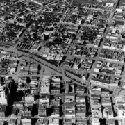 Aerial view of Cherry Creek floodwater and damage in Denver, Colorado after the Castlewood Canyon Dam break; shows the Auraria neighborhood (upper center), Colfax Street (upper left), Cherry Creek, and downtown buildings including the Telephone and Telegraph building (foreground).