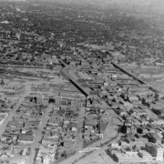 Aerial view of Cherry Creek floodwater and damage in Denver, Colorado after the Castlewood Canyon Dam break; shows the confluence of Cherry Creek and the South Platte River, railroad yards, viaducts, the Denver Tramway powerhouse, the Auraria and Highland neighborhoods, and downtown buildings including City Hall and Union Station.