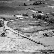 Aerial view of Cherry Creek flood damage in Denver, Colorado after the Castlewood Canyon Dam break; shows Cherry Creek, the washed out Harvard Avenue bridge, farms, and the Sullivan School.