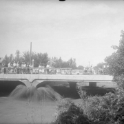 View of the Cherry Creek flood in Denver, Colorado after the Castlewood Canyon Dam break; shows people watching the torrent from a bridge.