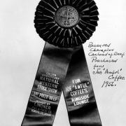 View of an award ribbon granted to Joe "Awful" Coffee's Ringside Lounge in Denver, Colorado; letters read: "Western Stock Show Association, Golden Anniversary National Western Stock Show, 1st Prize Beef, Bought by Lindner, Pkg. & Prov. Co." and "For Joe 'Awful' Coffee's Ringside Lounge."