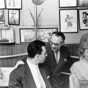 Interior view at the Ringside Lounge in Denver, Colorado; shows Joe "Awful" Coffee (with glasses), members of the Denver Bears baseball team, and women. Photographs of boxers, a comic strip, and a juke box selector are on the wall.