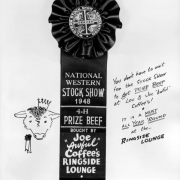 View of an award ribbon granted to Joe "Awful" Coffee's Ringside Lounge in Denver, Colorado; letters read: "Western Stock Show Association, National Western Stock Show 1948, 4-H Prize Beef, Bought by Joe 'Awful' Coffee's Ringside Lounge." Also shows a drawing of a cow with a crown.
