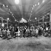 People crowd a tent theater at Lakeside Amusement Park in Lakeside (Jefferson County), Colorado for a beauty contest. Women wear hats and marcel hair styles.