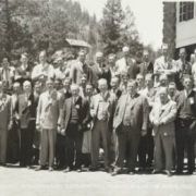 Group portrait of Alpha Kappa Psi fraternity members at Troutdale in the Pines (Jefferson County), Colorado; men's outfits include suits, golf pants, and argyle socks.